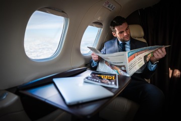 Byznysmen si čte noviny v letadle